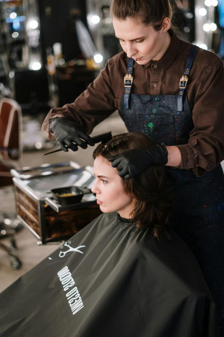 A hair stylist coloring a woman's hair in a salon. Professional hairdressing in action.